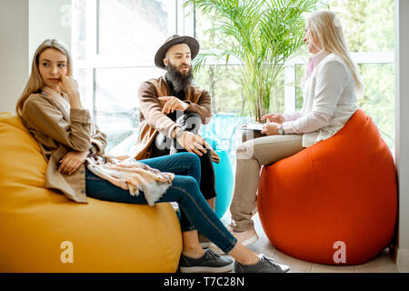 Young couple having misunderstandings during the psychological counseling with senior female psychologist in the office Stock Photo