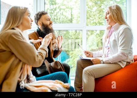 Young couple having misunderstandings during the psychological counseling with senior female psychologist in the office Stock Photo