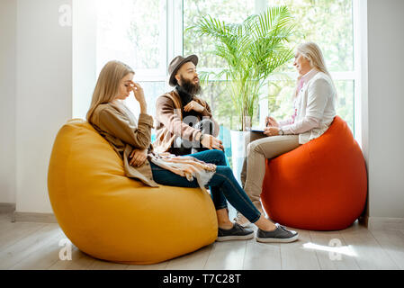 Young couple having misunderstandings during the psychological counseling with senior female psychologist in the office Stock Photo