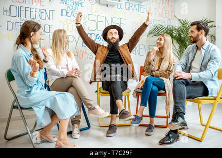 Young people sitting together during the psychological therapy, solving together some mental problems in the office Stock Photo