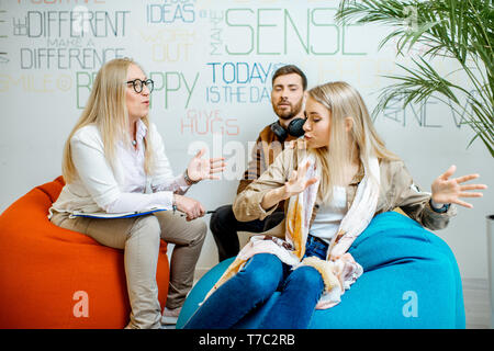 Young couple having misunderstandings during the psychological counseling with female psychologist in the modern office Stock Photo