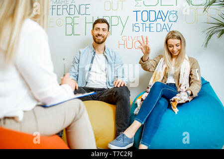 Young couple having misunderstandings during the psychological counseling with female psychologist in the modern office Stock Photo