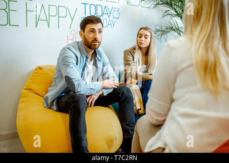 Young couple having misunderstandings during the psychological counseling with female psychologist in the modern office Stock Photo