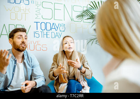 Young couple having misunderstandings during the psychological counseling with female psychologist in the modern office Stock Photo