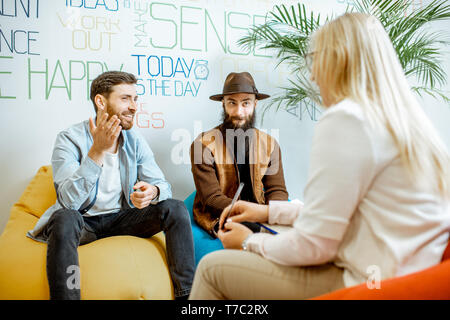 Homosexual couple during the psychological counseling with female psychologist in the modern office Stock Photo