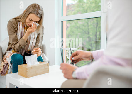 Young woman crying, having mental problems while sitting with psychologist during the psychological counseling in the office Stock Photo