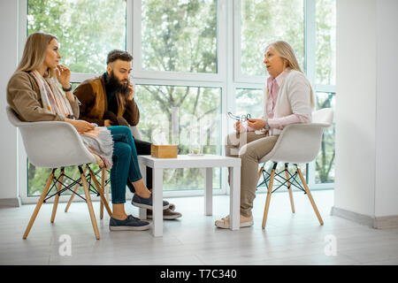 Young couple having misunderstandings during the psychological counseling with senior female psychologist in the office Stock Photo