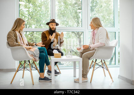 Young couple having misunderstandings during the psychological counseling with senior female psychologist in the office Stock Photo