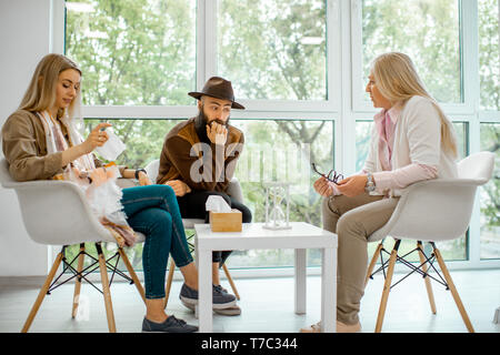 Young couple having misunderstandings during the psychological counseling with senior female psychologist in the office Stock Photo