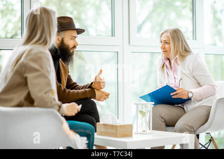 Young couple having misunderstandings during the psychological counseling with senior female psychologist in the office Stock Photo