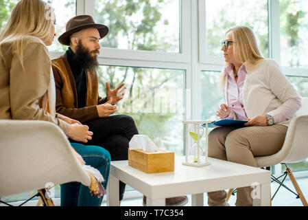 Young couple having misunderstandings during the psychological counseling with senior female psychologist in the office Stock Photo