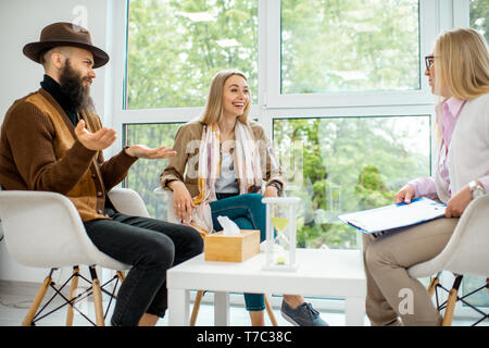 Young couple having misunderstandings during the psychological counseling with senior female psychologist in the office Stock Photo