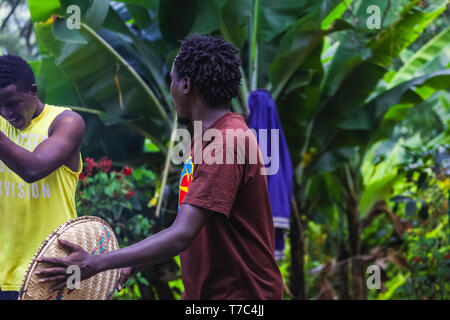 African men singing and dancing their traditional songs for the tourists. Holding tambourine in a hand and beating the beat. Wearing casual t-shirts, Stock Photo