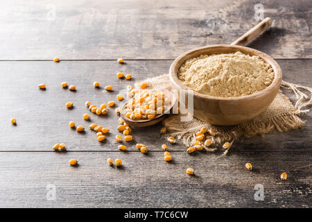 Corn flour in bowl on wooden table Stock Photo