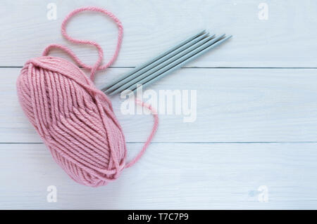 Pink skein with knitting needles isolated on white wooden background, knitting mittens or socks on 5 needles Stock Photo