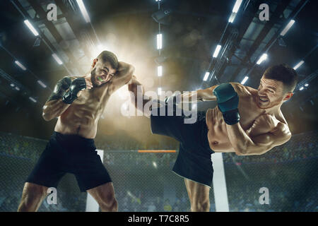 Hit for one step to the win. Two professional fighters posing on the sport boxing ring. Couple of fit muscular caucasian athletes or boxers fighting. Sport, competition and human emotions concept. Stock Photo