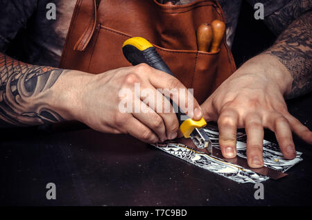 Leather Worker cutting out leather goods in a workshop Stock Photo