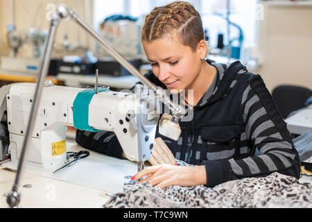 Seamstress sewing at machine, portrait. Female tailor stitching material at workplace. Preparing fabric for clothes making. Tailoring, garment industr Stock Photo