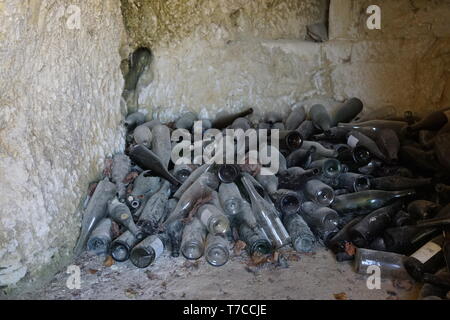 pile of old dusty glass wine bottles in a troglodyte cave in the Loire valley, France Stock Photo