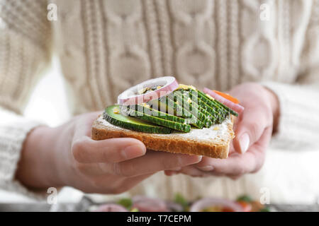 Woman holding delicious toast with avocado, closeup Stock Photo
