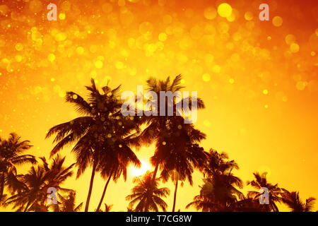 Palm trees silhouettes at sunset with party gold glitter lights bokeh overlay effect Stock Photo