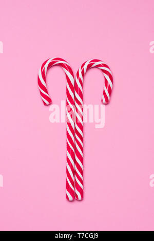 Two traditional shiny striped candy canes on pink background flatlay Stock Photo