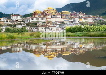 Songzanlin Tibetan Buddhist Monastery reflected in sacred lake, Shangri-La, Yunnan Province, China Stock Photo