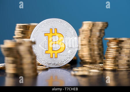 Bitcoin. Bitcoin coin between golden coins stacks with reflection. Stock Photo