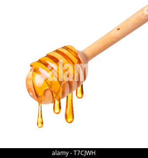 Honey dripping from wooden dipper spoon isolated on white background Stock Photo