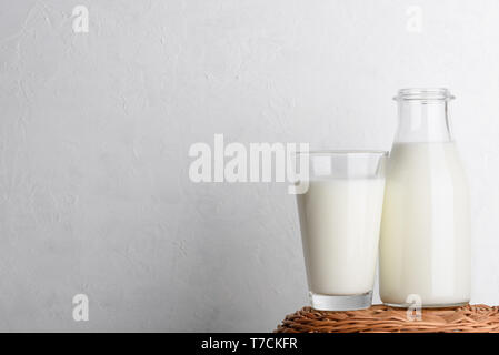 Bottle and glass of milk on wicker basket and white wall background Stock Photo
