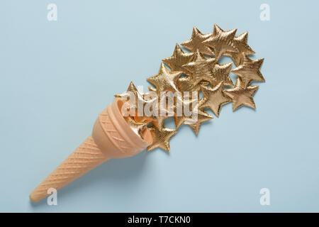 Ice cream cone with shiny golden stars on blue pastel background top view Stock Photo