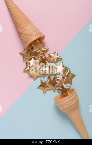 Two ice cream wafer cones with golden stars on blue and pink pastel background top view Stock Photo