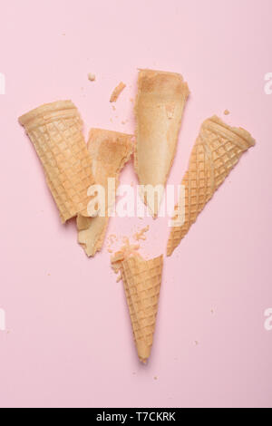 Crushed empty ice cream waffle cone on pink pastel background Stock Photo