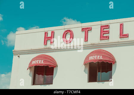 Old unclean hotel facade with vintage neon sign retro color stylized Stock Photo