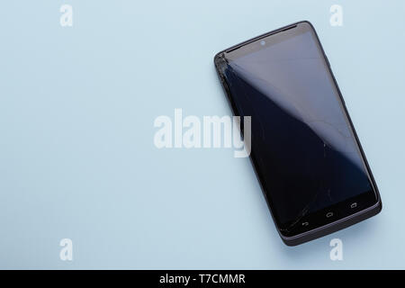 Broken screen smartphone shattered glass on blue background top view Stock Photo