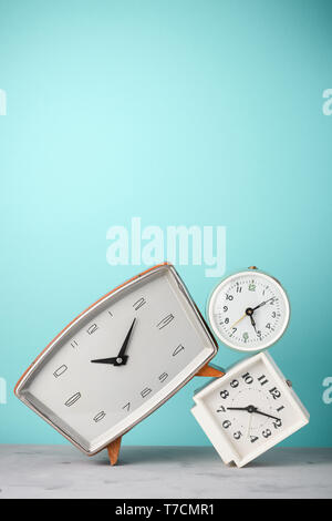 Retro alarm clocks tilted and stacked time concept on vintage blue background Stock Photo