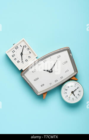 Different retro clocks on blue pastel background time concept flat lay top view Stock Photo