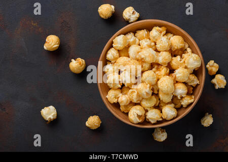 Caramel popcorn in bowl on dark table background top view Stock Photo