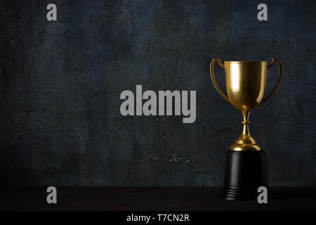 Golden trophy cup on table dark background with copy space Stock Photo