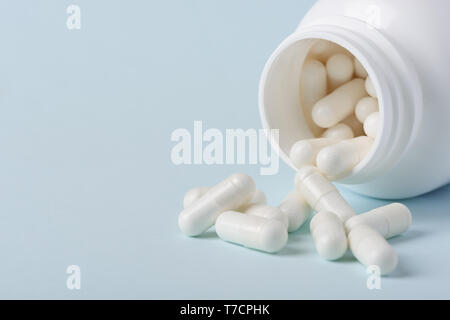 Drugs in bottle spill on blue background with copy-space Stock Photo