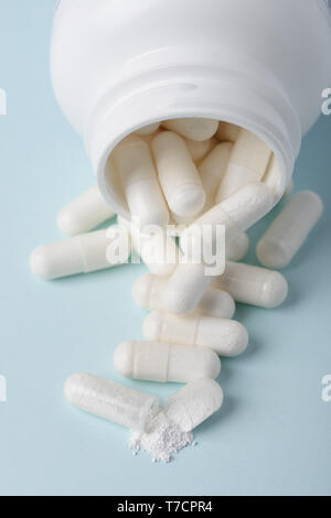 Pills spill from bottle with one open with white powder substance Stock Photo