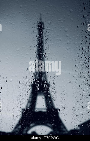 Paris Eiffel tower dark silhouette at rainy day. Water drops on the window. Stock Photo