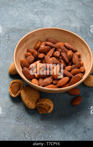 Fried salted almond nuts in a ceramic bowl on rustic background Stock Photo