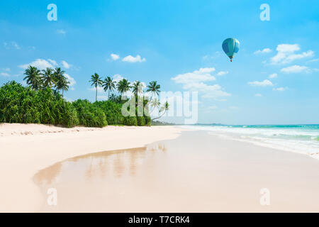 Untouched tropical beach. Empty vacation island coast with palm trees and hot air balloon in the sky. Stock Photo
