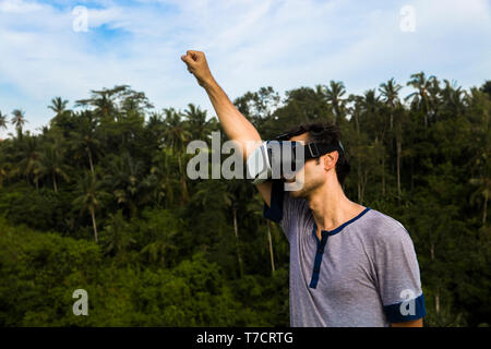 Young man wearing VR glasses in the tropicalforest Stock Photo