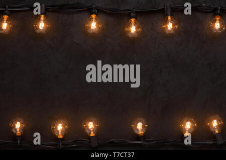 Light bulbs retro garland on dark black wall background Stock Photo