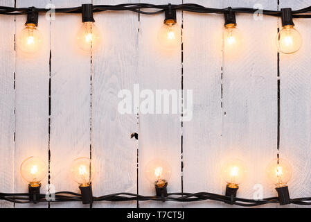 Light bulbs garland on old painted wooden wall frame Stock Photo