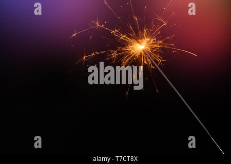 Sparkler burining glittering candle magic festive light on dark background. Christmas party sparkler or Bengal fire. Stock Photo