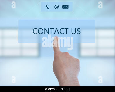 Contact us text button with symbols on invisible display being pressed by person using index finger as support concept closeup Stock Photo