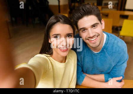 Image of a young students friends couple in library doing homework studying take a selfie by camera. Stock Photo